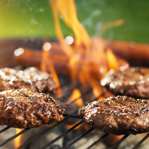 burgers being cooked over charcoal grill